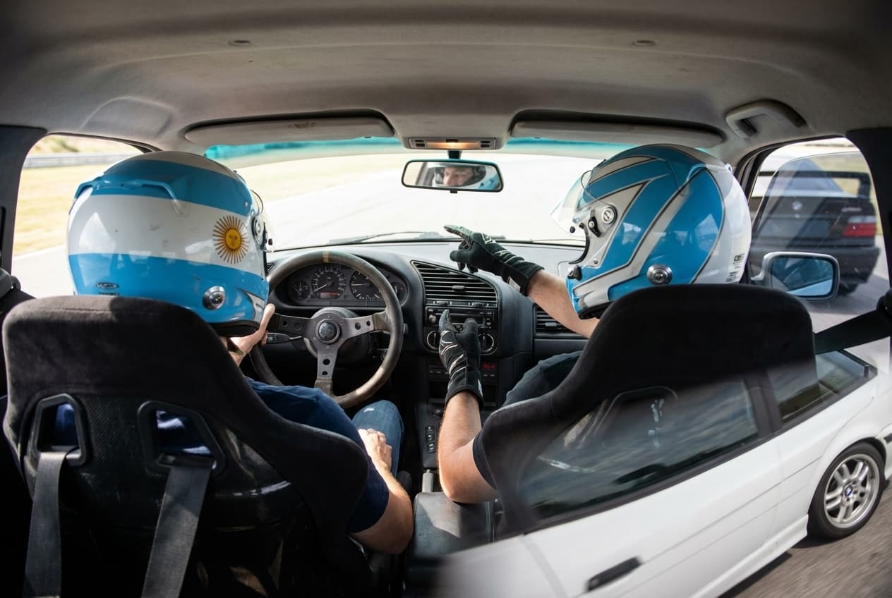 Interior del BMW E36 con piloto y pasajero con cascos de seguridad