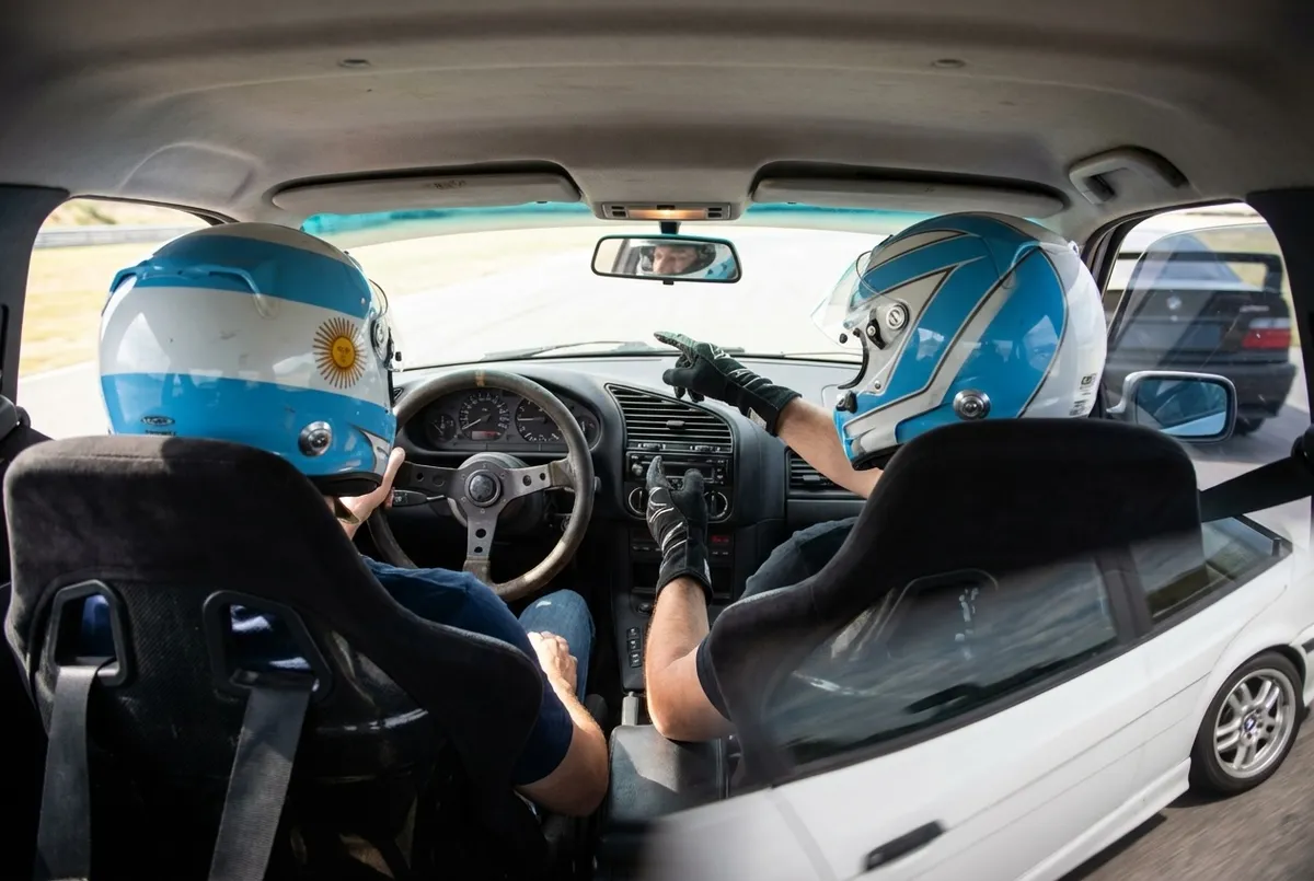 Interior del BMW E36 con piloto y pasajero con cascos de seguridad
